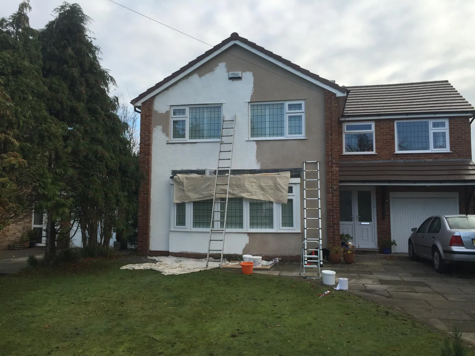 Detached house mid-job with first base coats applied and ladders up